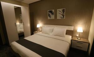 科威特Le Paris Residency Sabah Al Salem的一间卧室配有一张大床,桌子上放着两盏灯