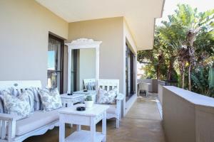 德班Teremok Lodge & Spa的一个带白色家具和棕榈树的门廊