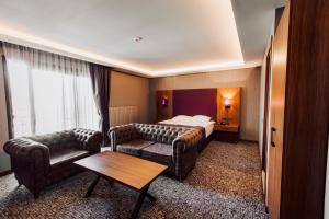 科贾埃利Business Palas Otel的酒店客房配有床、沙发和桌子。