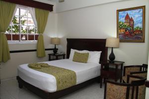 圣地亚哥洛斯卡巴皮拉提诺赌场酒店的一间卧室配有一张大床和两把椅子