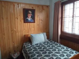 波哥大卡萨波萨达阿梅利亚酒店的卧室配有一张床,墙上挂有绘画作品