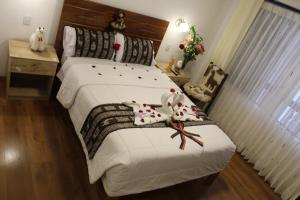 库斯科Cusco Hostal Qolla Wasi的一间卧室配有一张白色大床,床上有鲜花