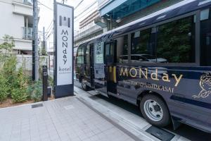 东京hotel MONday Tokyo Nishikasai的公共汽车停在一个公共汽车站旁边