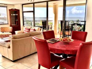 凯恩斯Cairns Apartment Esplanade Ocean Views的客厅配有红色的桌子和椅子