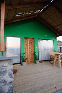 玛尔盖姆拉The green and red cabins的绿色房子,配有桌子和木地板