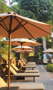 沙努尔Besakih Beach Hotel的庭院里摆放着一排椅子和遮阳伞