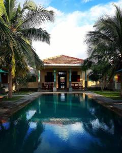 卡尔皮蒂耶Villa Setha Wadi的棕榈树屋前的游泳池