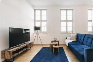 德累斯顿Apartment direkt an der Frauenkirche, Jüdenhof, FEWO-Residenz-Dresden的客厅配有蓝色的沙发和平面电视。