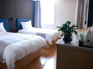 济阳尚客优精选山东济南济阳县华阳路店的一间酒店客房,配有两张床和一张桌子上的植物