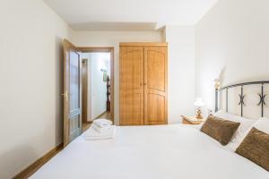 卡尼略Apartamento Refugi的卧室配有白色的床和木制橱柜。