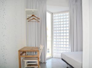 卡塔赫纳LoopINN Hostel Cartagena的一间卧室配有书桌、床和窗户。