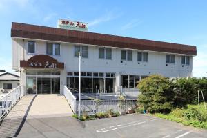 三沢市Hotel Tensui的前面有停车位的大楼