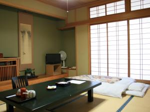 千曲市旬树庵柏屋传统日式旅馆的一间卧室配有一张床和一张带茶几的桌子