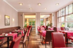 不来梅港阿马里斯酒店的餐厅设有红色的桌椅和窗户。