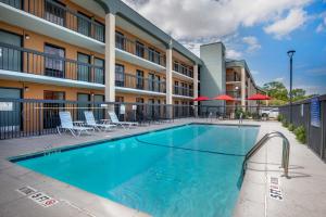 沃思堡Quality Inn West Fort Worth的酒店前的游泳池配有椅子和遮阳伞