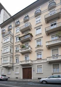 都灵B&B Torino Crocetta的带阳台的建筑,前面设有停车场