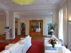 汉堡康莫德瑞酒店的客厅配有白色沙发和红色地毯。