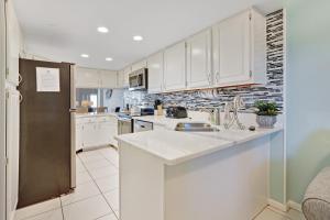 德斯坦Inlet Reef的厨房配有白色橱柜和不锈钢冰箱