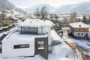 迈斯霍芬lake and mountains appartements的雪中白房子,背景是群山