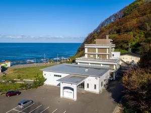 鹤冈市庄内阳光度假酒店的一座拥有停车场的建筑,毗邻大海