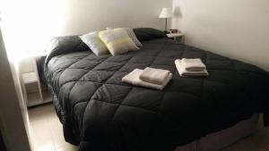 El PalomarAloha III - El Palomar B&D的一间卧室配有一张黑色床和两条毛巾