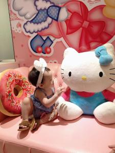 东港幸福浪漫旅的坐在巨型泰迪熊旁边床边的小女孩