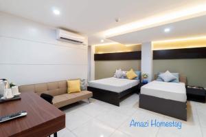 杜马格特Amazi Homestay-Dumaguete的客房设有两张床、一张沙发和一张书桌。