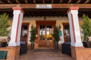 埃尔罗西奥拉方达德尔罗西奥乡村旅馆的一座种植盆栽植物的建筑的前门