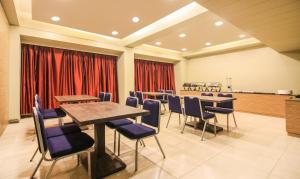 孟买The Legend Hotel- Santacruz Near Mumbai International Airport的一间会议室,配有桌椅和红色窗帘