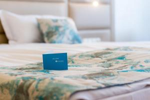 内塞伯尔Bilyana Beach Hotel - All Inclusive & Free Beach Access的床上的蓝色标志