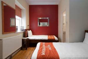 布莱顿霍夫Amsterdam Hotel Brighton Seafront的一间卧室设有两张床和红色的墙壁