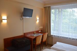 汉堡Hotel Wikinger Hof的酒店客房设有一张桌子和一台墙上的电视