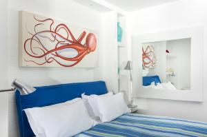 维克艾库塞Capo la Gala Hotel&Wellness的卧室配有蓝色的床和墙上的绘画作品
