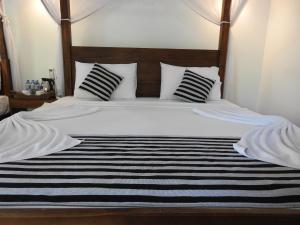 达瓦拉维Jungle Paradise的一张带黑色和白色条纹床单和枕头的床