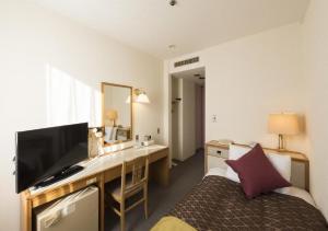 鱼津skyhotel uozu / Vacation STAY 59574的酒店客房配有一张桌子、一张床和一台电视