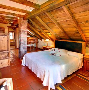 Vibaño魔法山乡村旅馆的一间带白色床铺的卧室,位于带木制天花板的客房内。