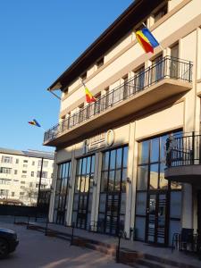 BîrladHotel Ro&Mario Barlad的上面有两面旗帜的建筑