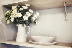普雷里德欣Waterfront Hotel的花瓶,在货架上放着白色花,放着碗