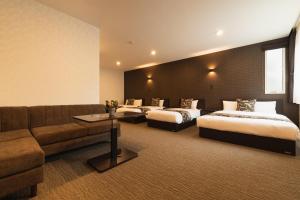 长崎GRAND BASE Nagasaki Ekimae的酒店客房,设有两张床和一张沙发