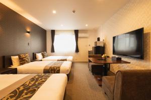 长崎GRAND BASE Nagasaki Ekimae的酒店客房设有两张床和一台平面电视。