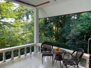 俊穆岛Koh Jum Serenity Resort的一个带椅子和桌子的门廊,享有树林的景色