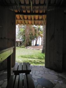 库穆鲁沙蒂巴Hospedaria Cumuruxatiba的坐在大楼入口处的木凳