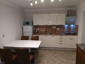 多莱尼斯凯托普利采Apartmaji Maln的厨房配有白色橱柜和桌椅