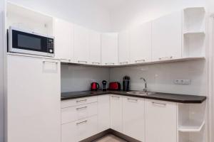 布达佩斯Contemporary City Apartment Váci Utca的白色的厨房配有白色的橱柜和微波炉
