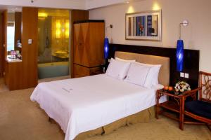 惠州惠州康帝国际酒店的卧室配有一张白色大床和一把椅子
