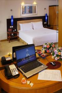 惠州惠州康帝国际酒店的一张带笔记本电脑的桌子、一部电话和一张床