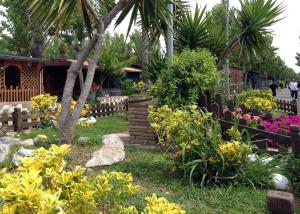阿尔代亚Onda Camping Village的一座花园,花园内种有五颜六色的鲜花,设有木栅栏