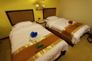龙运SIX VILLA INN的两张位于酒店客房的床,上面有鲜花