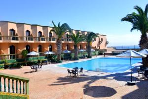 萨菲Hôtel Atlantique Panorama的一个带棕榈树和椅子的游泳池的度假酒店