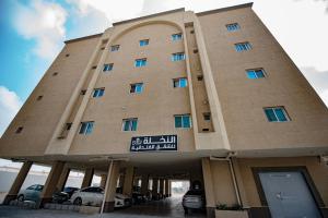 胡富夫Al Nakhla Aparthotel的一座大型建筑,前面有汽车停放